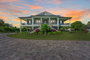 A stunning home with a brick driveway, showcasing the art of home building, bathed in the warm hues of a mesmerizing sunset.