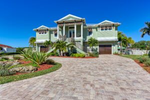 A home with a brick driveway and palm trees, perfect for waterfront builds.